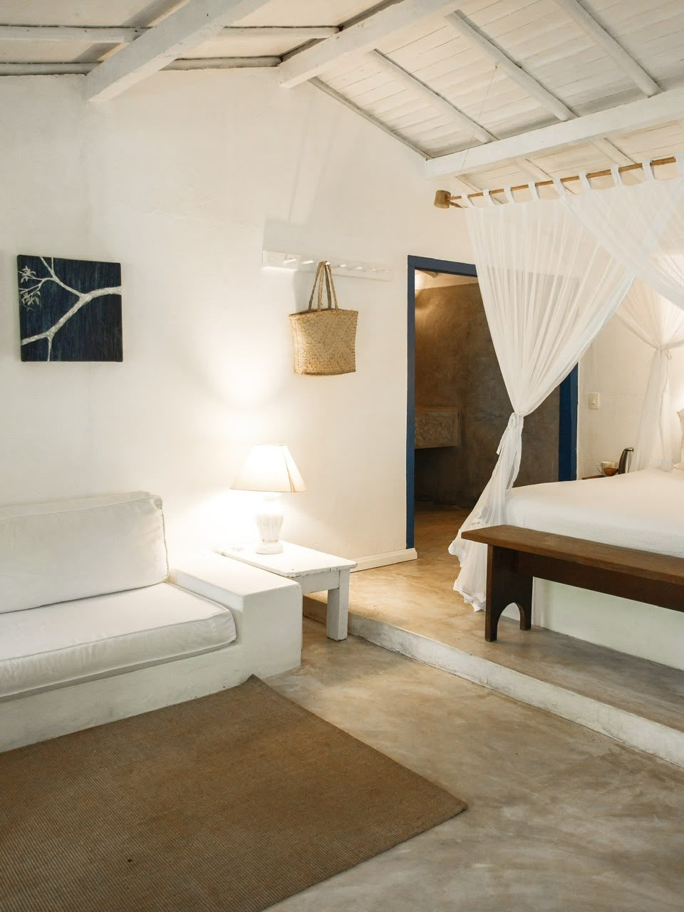 Área de estar do Bangalô Azul com sofá branco e quadro em tons de azul