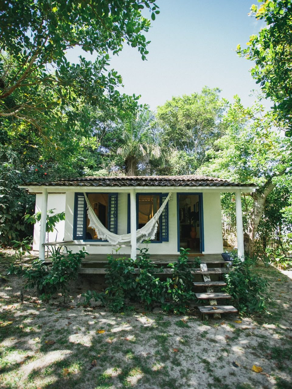 Fachada do Bangalô Azul com rede na varanda, entre as árvores
