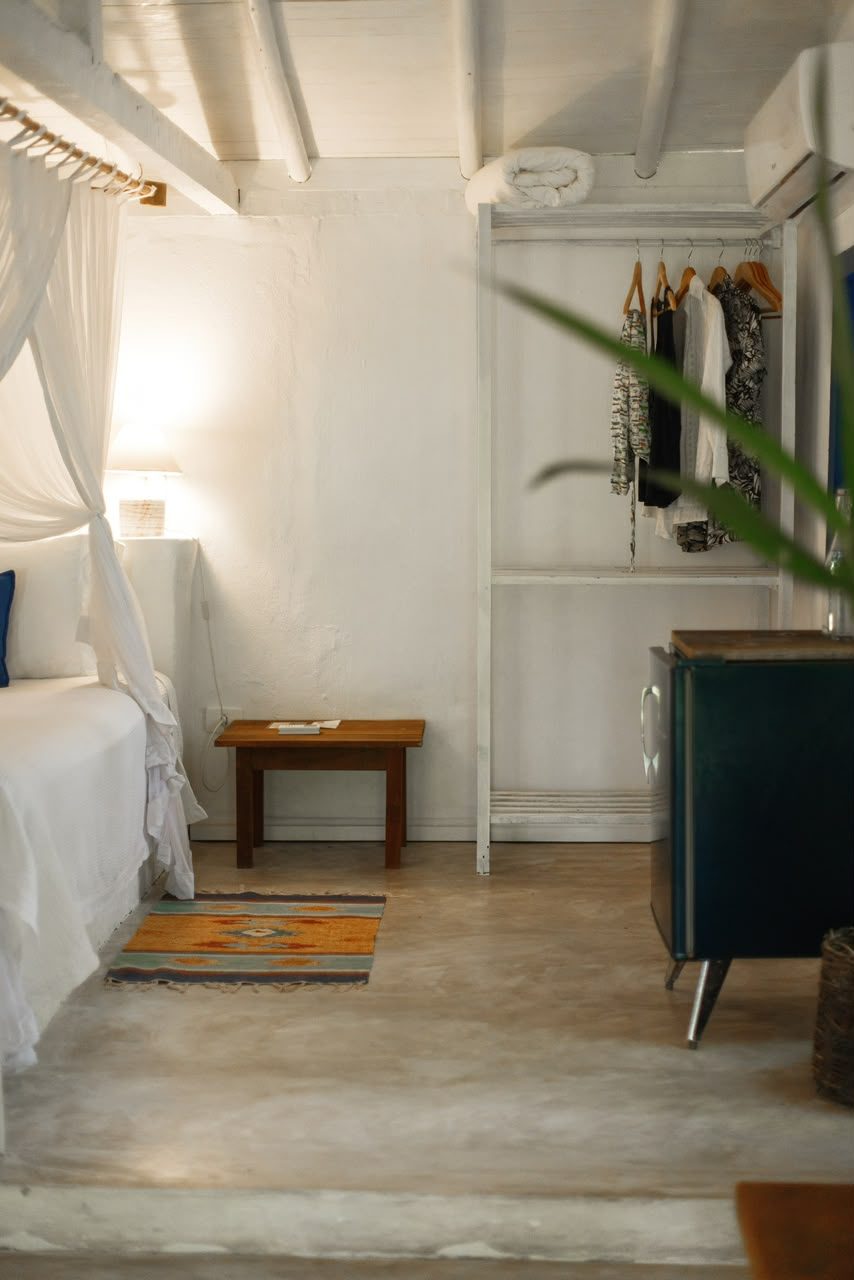 Arara de roupas e frigobar no quarto do Bangalô Azul