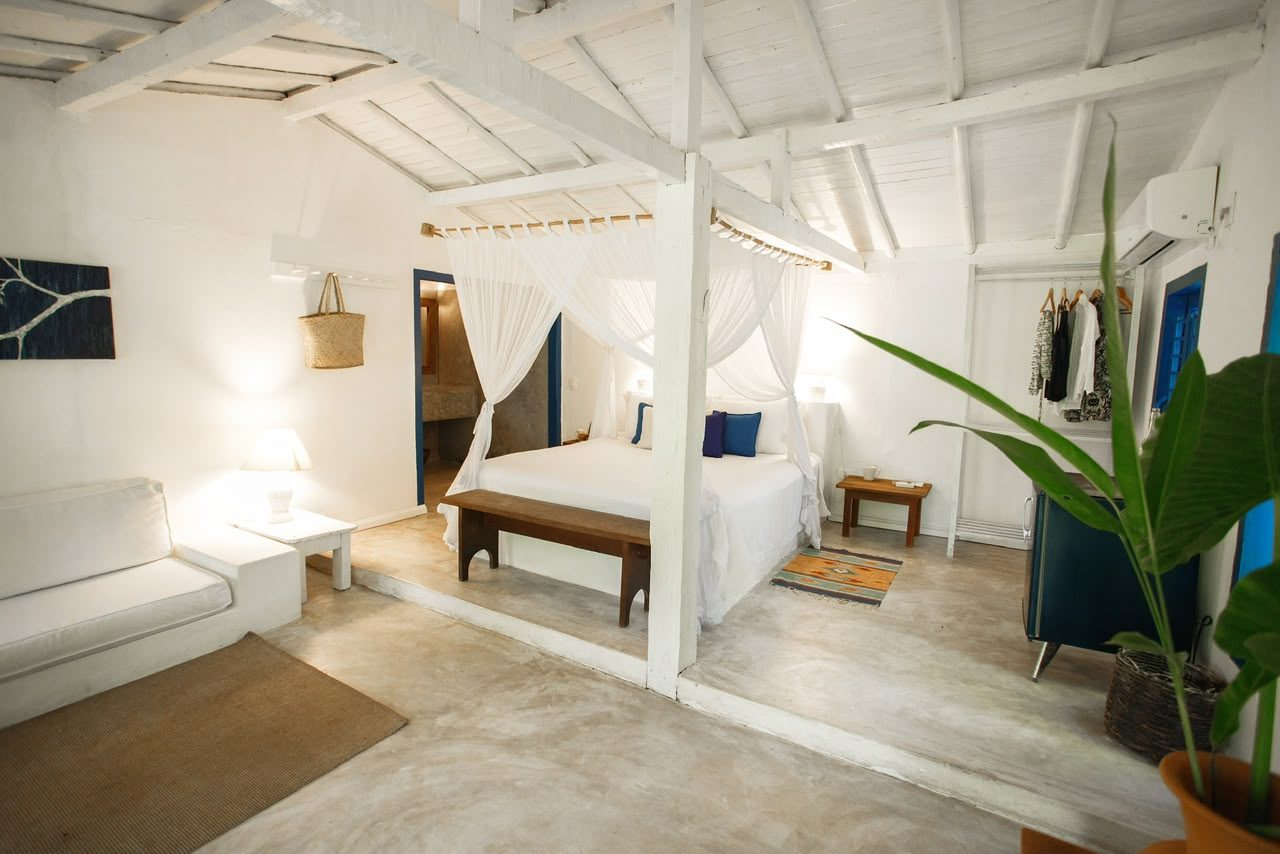 Quarto do Bangalô Azul com cama de dossel, sofá e área de estar