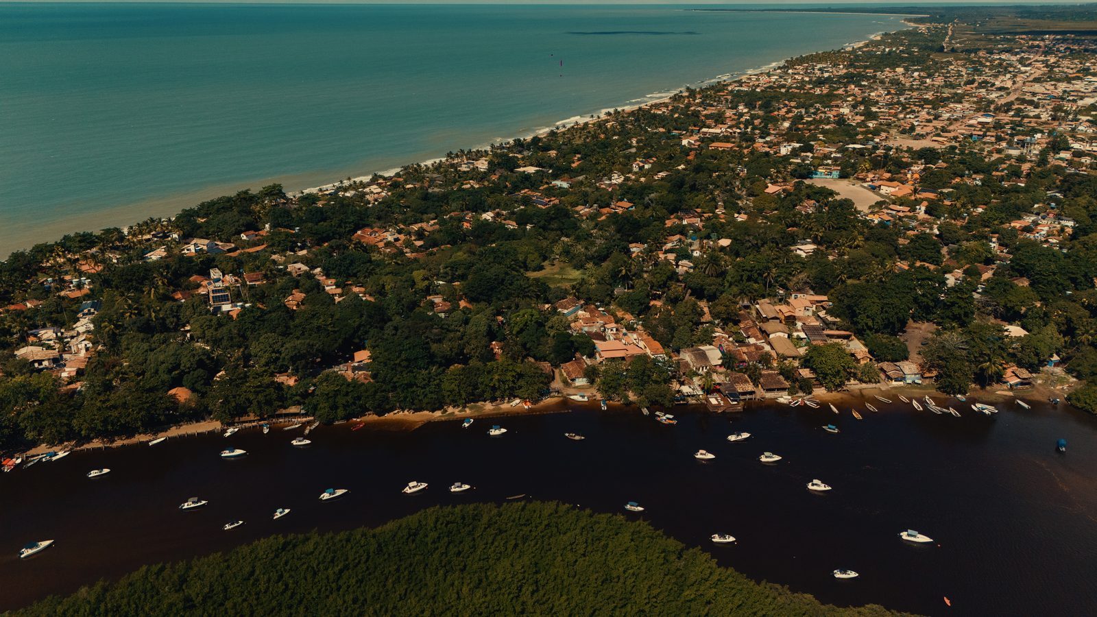 Vista aérea da vila de Caraíva, rio, mar e casas
