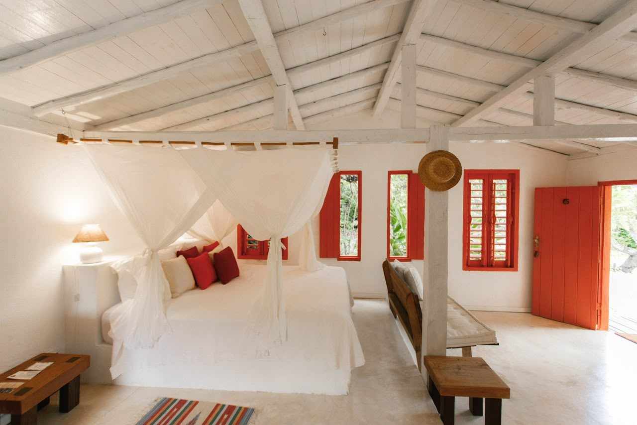 Quarto do Bangalô Laranja com cama de dossel e portas laranja abertas